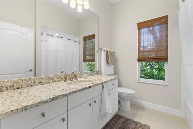 a bathroom with a granite countertop sink toilet and mirror