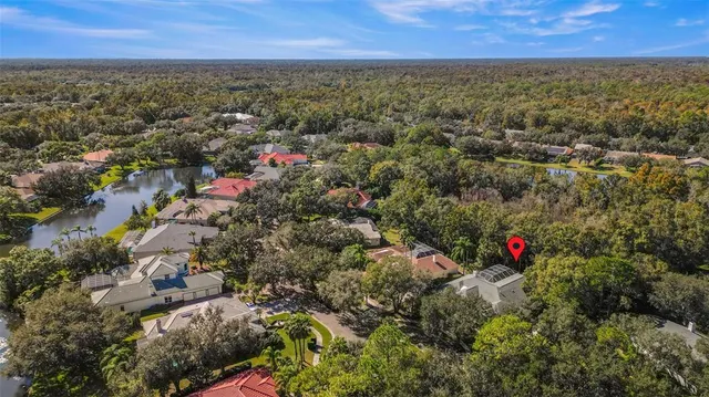 an aerial view of residential house with outdoor space and trees all around