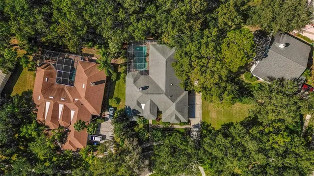 an aerial view of a house with yard and large trees