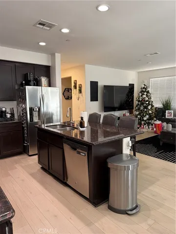 a living room with stainless steel appliances kitchen island granite countertop a stove and a sink