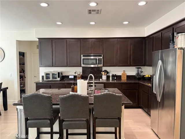 a kitchen with granite countertop a refrigerator stove microwave and cabinets