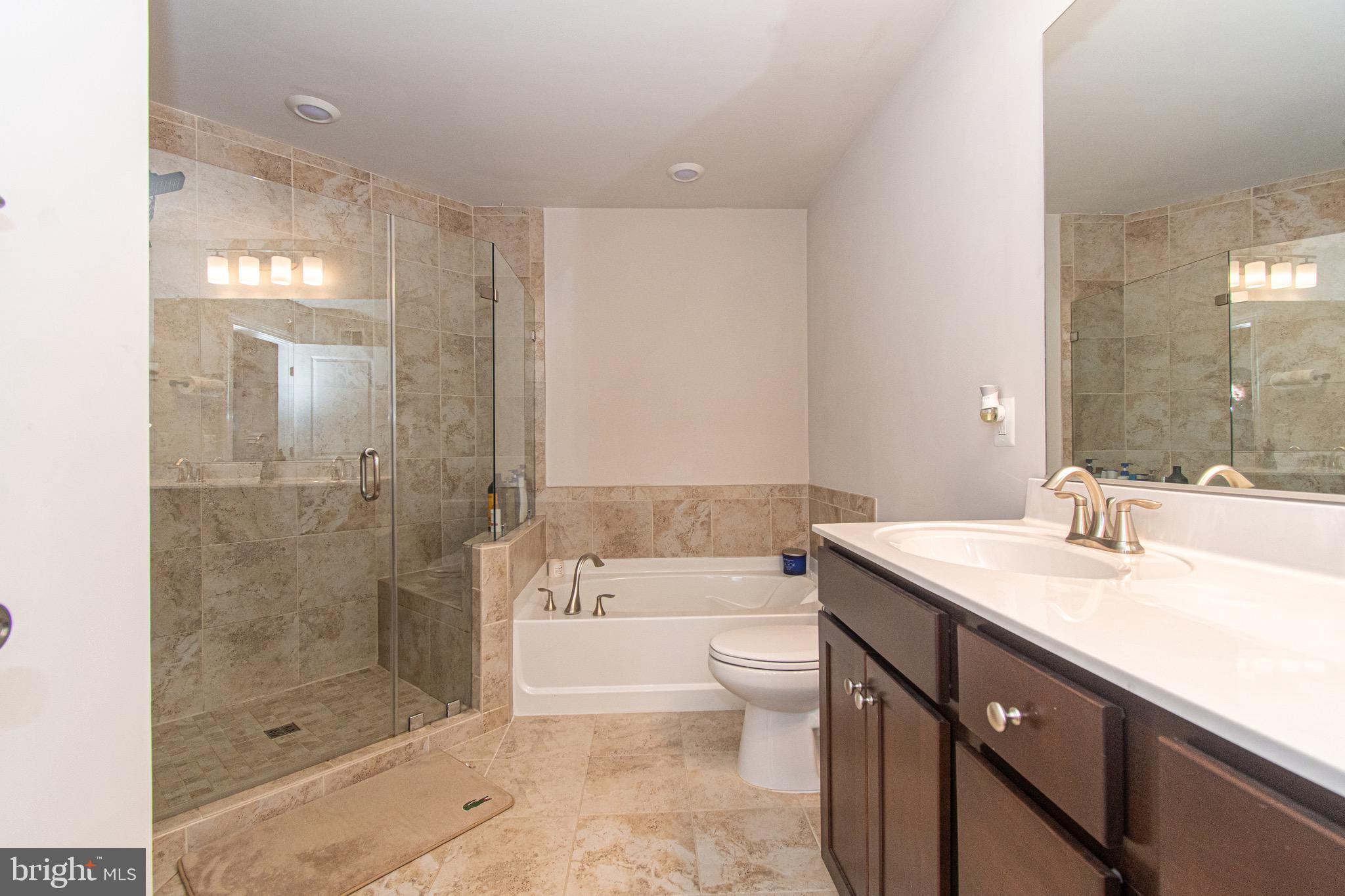 9637 Block Street Lanham, MD 20706 - Photo 25 of 47 a bathroom with a granite countertop sink a toilet a mirror and bathtub