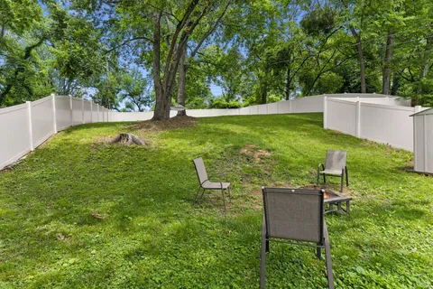 a backyard of a house with table and chairs a large tree