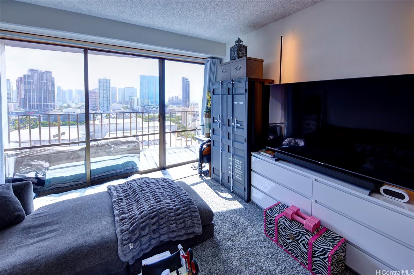 700 Richards Street, Unit 1708 Honolulu, HI 96813 - Photo 7 of 25 a living room with furniture a flat screen tv and a floor to ceiling window