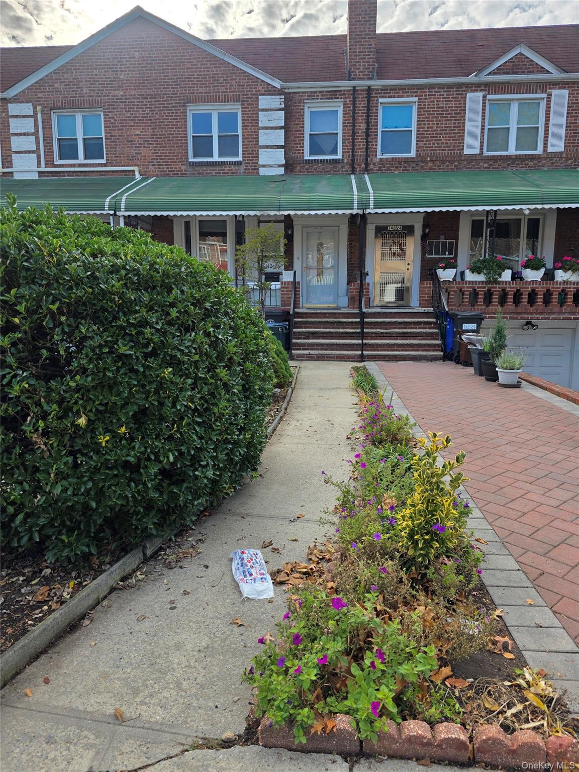 View of front of house featuring a porch, brick siding, and a chimney