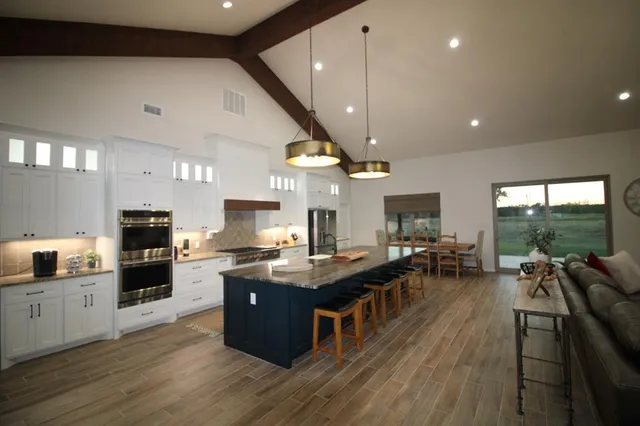 a kitchen with stainless steel appliances kitchen island granite countertop a stove and a large countertops with wooden floor