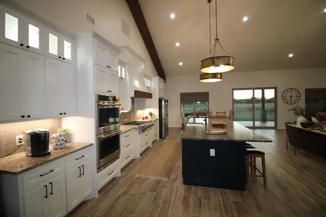 a kitchen with stainless steel appliances granite countertop sink stove and wooden floor