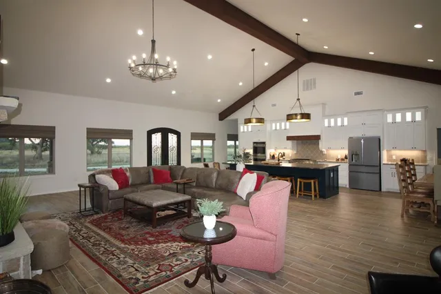 a living room with furniture kitchen view and a chandelier