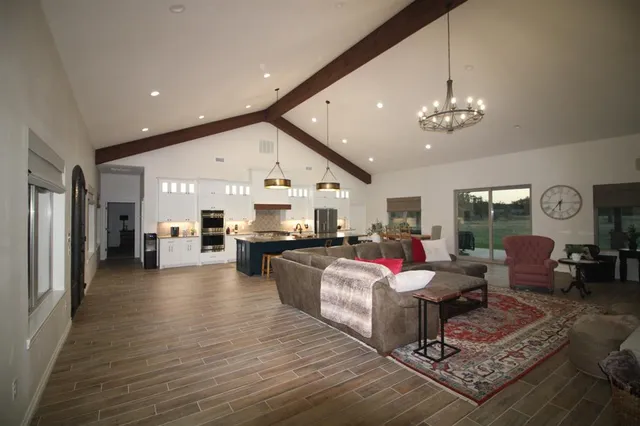 a living room with furniture kitchen view and a chandelier