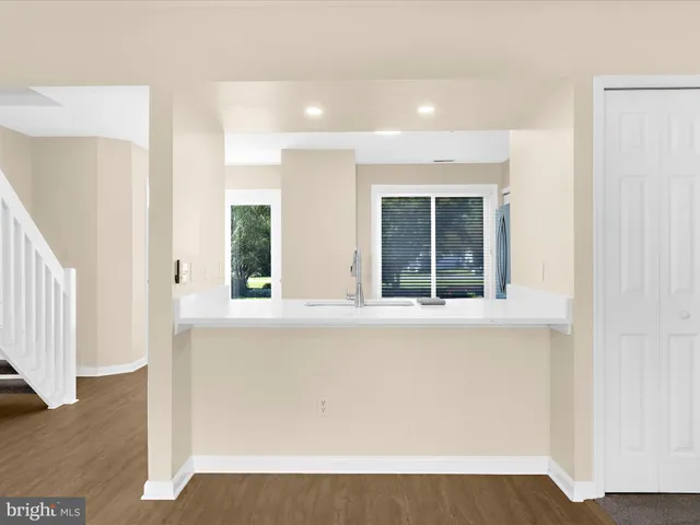 a view of an empty room with wooden floor and stairs