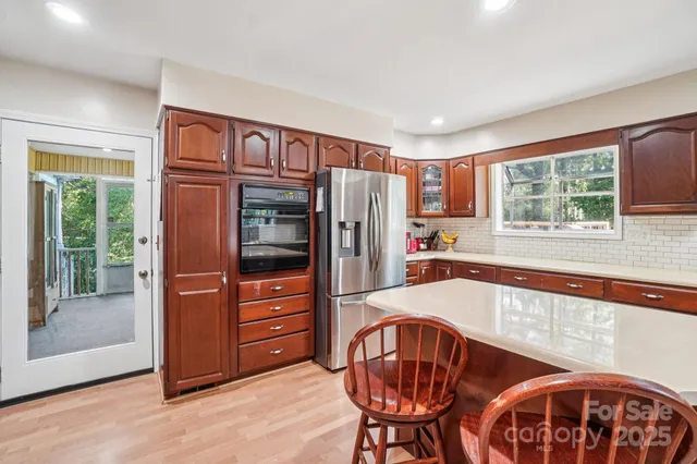 a kitchen with stainless steel appliances granite countertop a refrigerator a stove a dining table and chairs with wooden floor