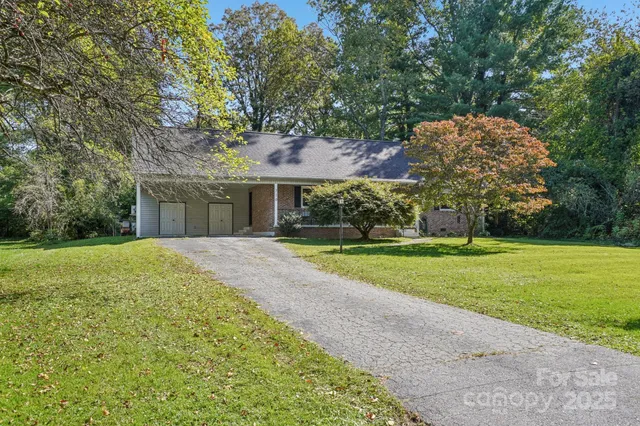 a view of a house with a big yard and large trees