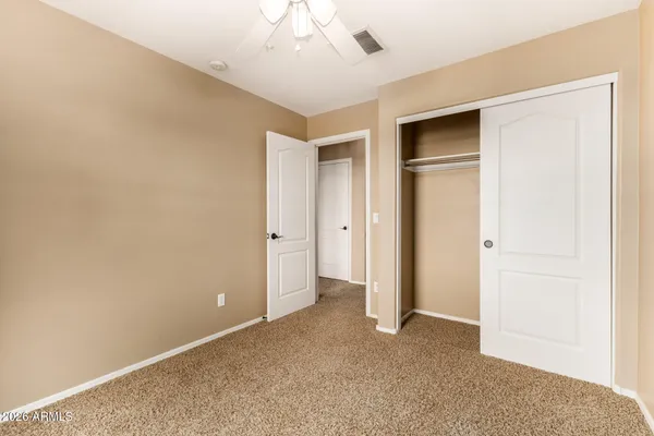 an empty room with closet and a ceiling fan