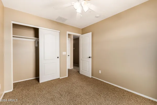 an empty room with closet and a chandelier fan