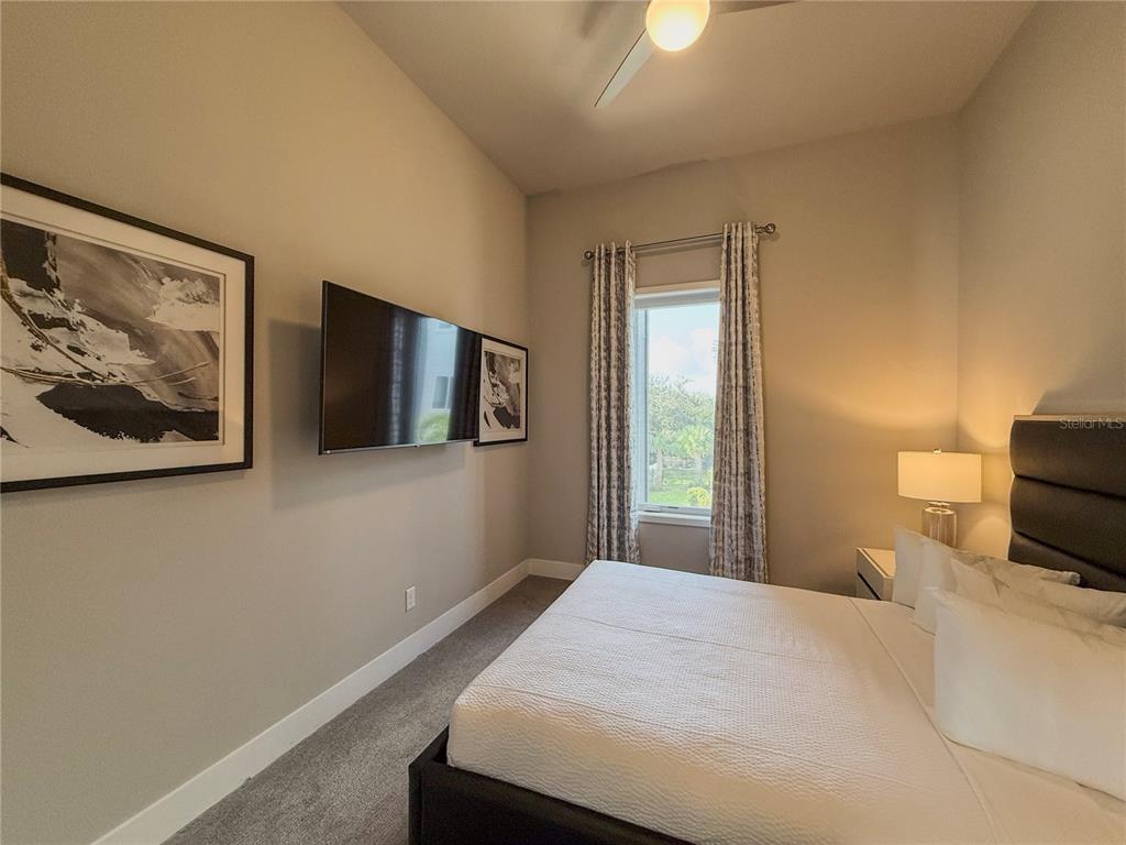 7770 Sandy Ridge Drive, Unit 231 Reunion, FL 34747 - Photo 14 of 25 a bedroom with a bed and a flat screen tv
