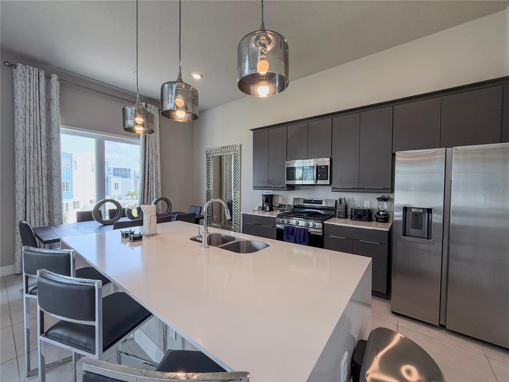 7770 Sandy Ridge Drive, Unit 231 Reunion, FL 34747 - Photo 4 of 25 a kitchen with a dining table cabinets stainless steel appliances and a chandelier