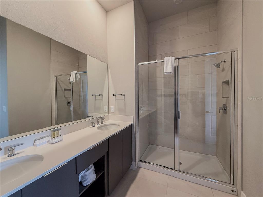 7770 Sandy Ridge Drive, Unit 231 Reunion, FL 34747 - Photo 7 of 25 a bathroom with a shower sink vanity and mirror