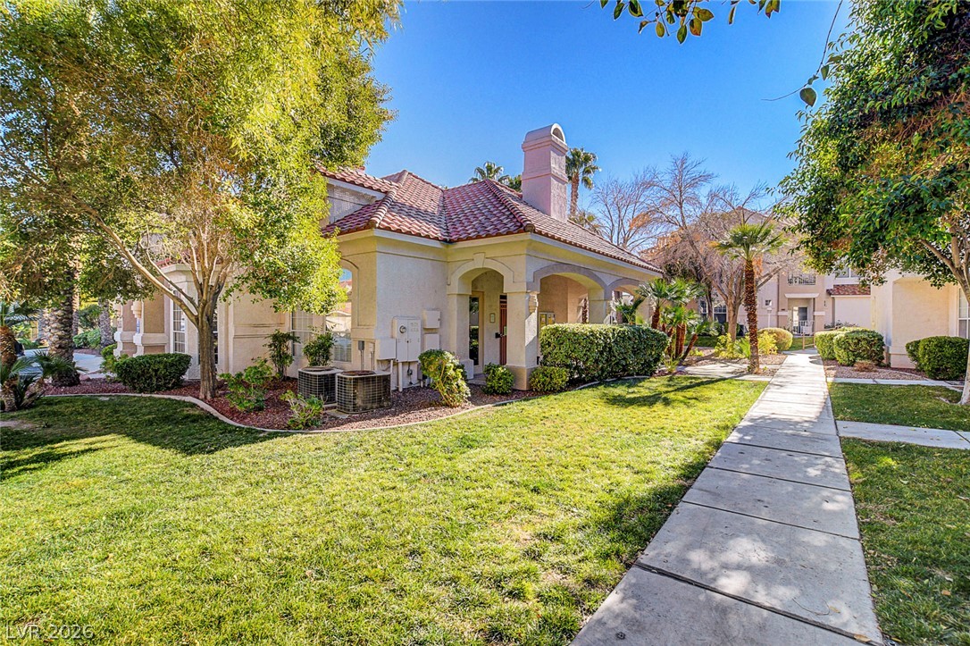 8555 West Russell Road, Unit 1017 Las Vegas, NV 89113 - Photo 29 of 34 A terracotta-tiled roof crowns this charming, stucco-finished building, framed by verdant landscaping and a welcoming pathway.