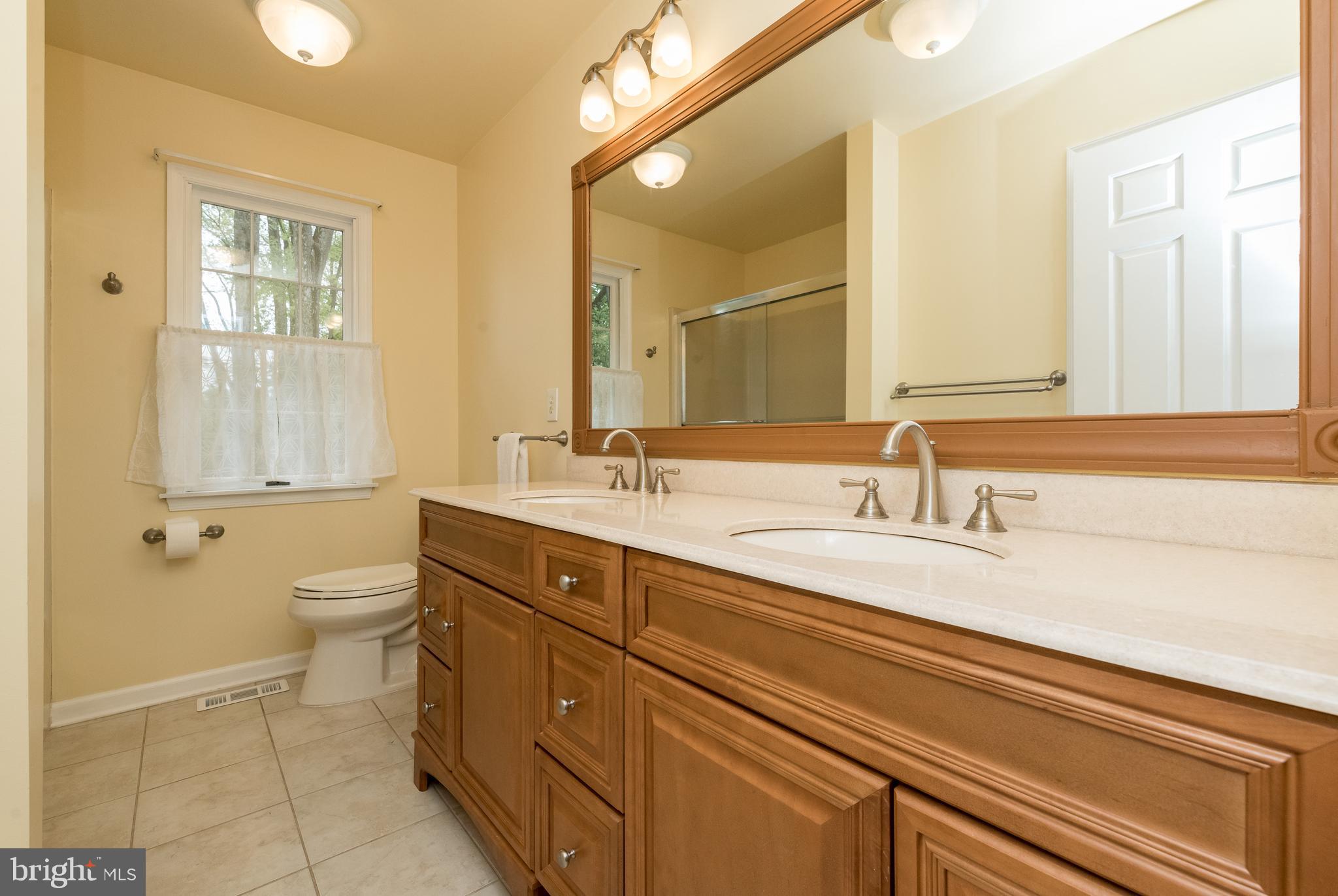 1007 Valewood Road Towson, MD 21286 - Photo 30 of 49 a bathroom with a double vanity sink a toilet and a mirror