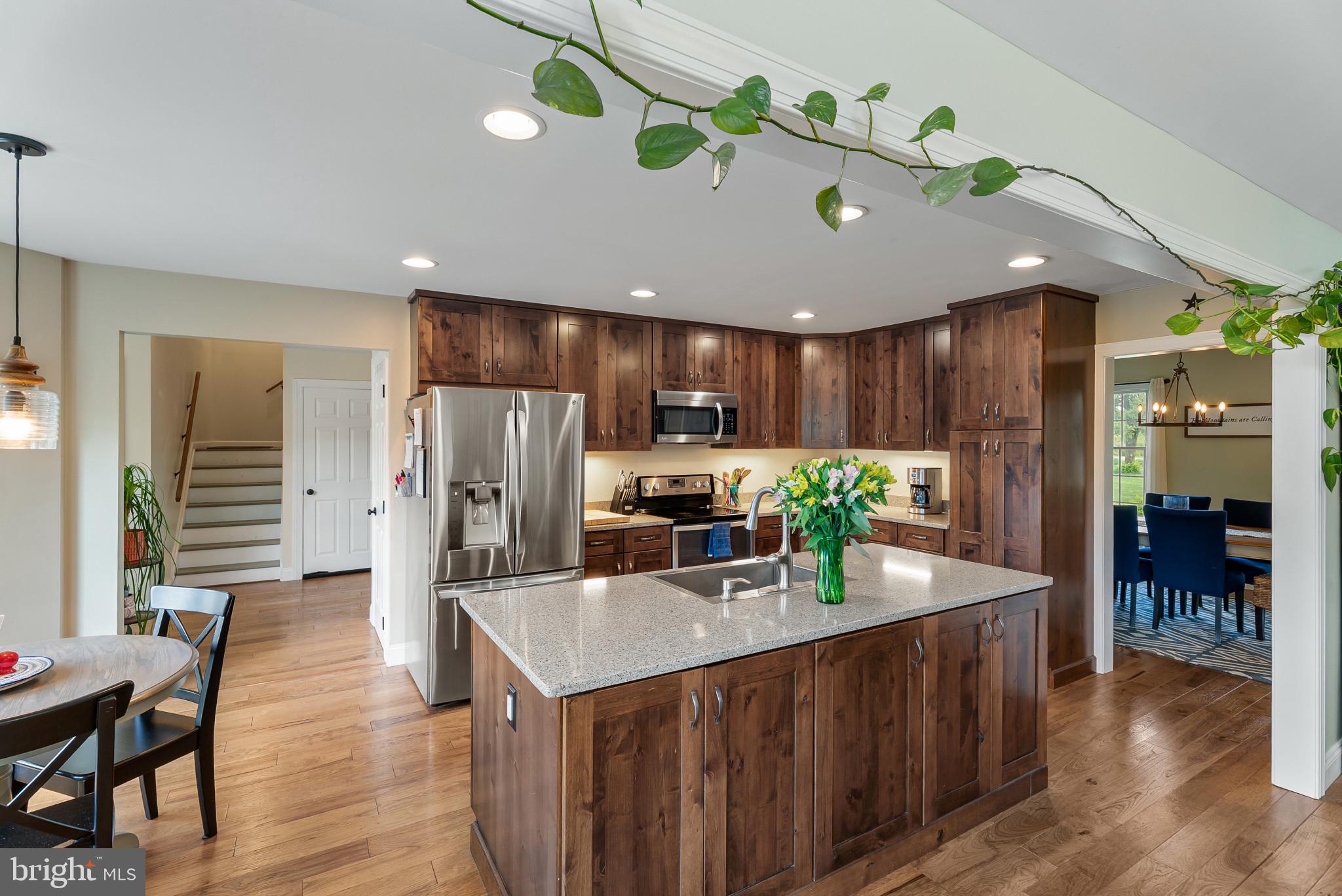 418 North Clear Ridge Road Union Bridge, MD 21791 - Photo 15 of 49 a kitchen with stainless steel appliances granite countertop a refrigerator a sink dishwasher and a dining table with wooden floor