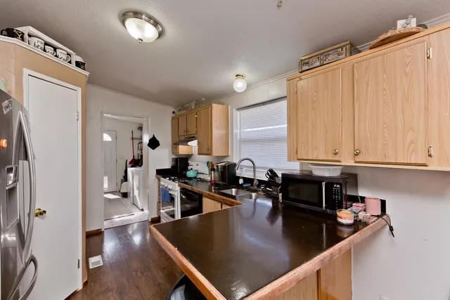 a kitchen with stainless steel appliances granite countertop a refrigerator a stove and white cabinets with wooden floor