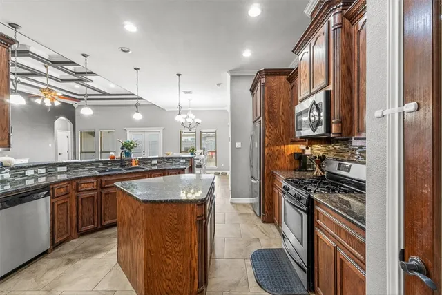 a kitchen with stainless steel appliances granite countertop a sink a stove and a refrigerator