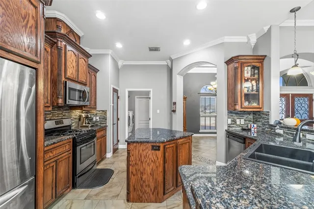 a kitchen with stainless steel appliances granite countertop a refrigerator a stove and a sink