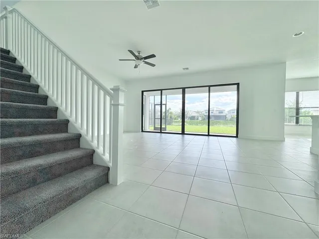 an empty room with windows and ceiling fan