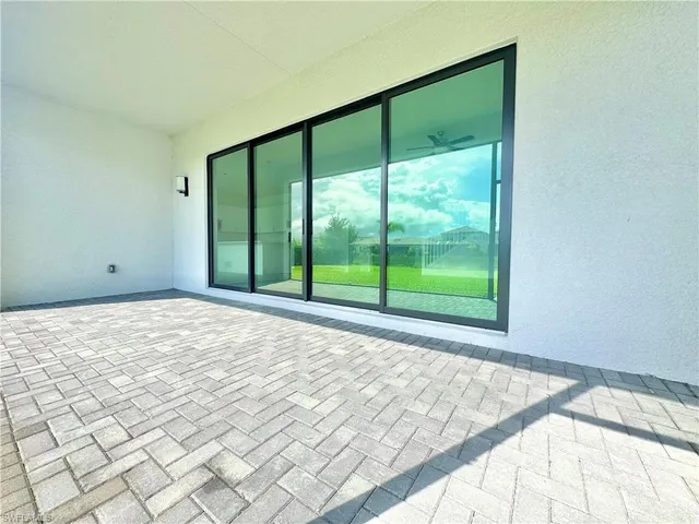 an empty room with windows and chandelier fan