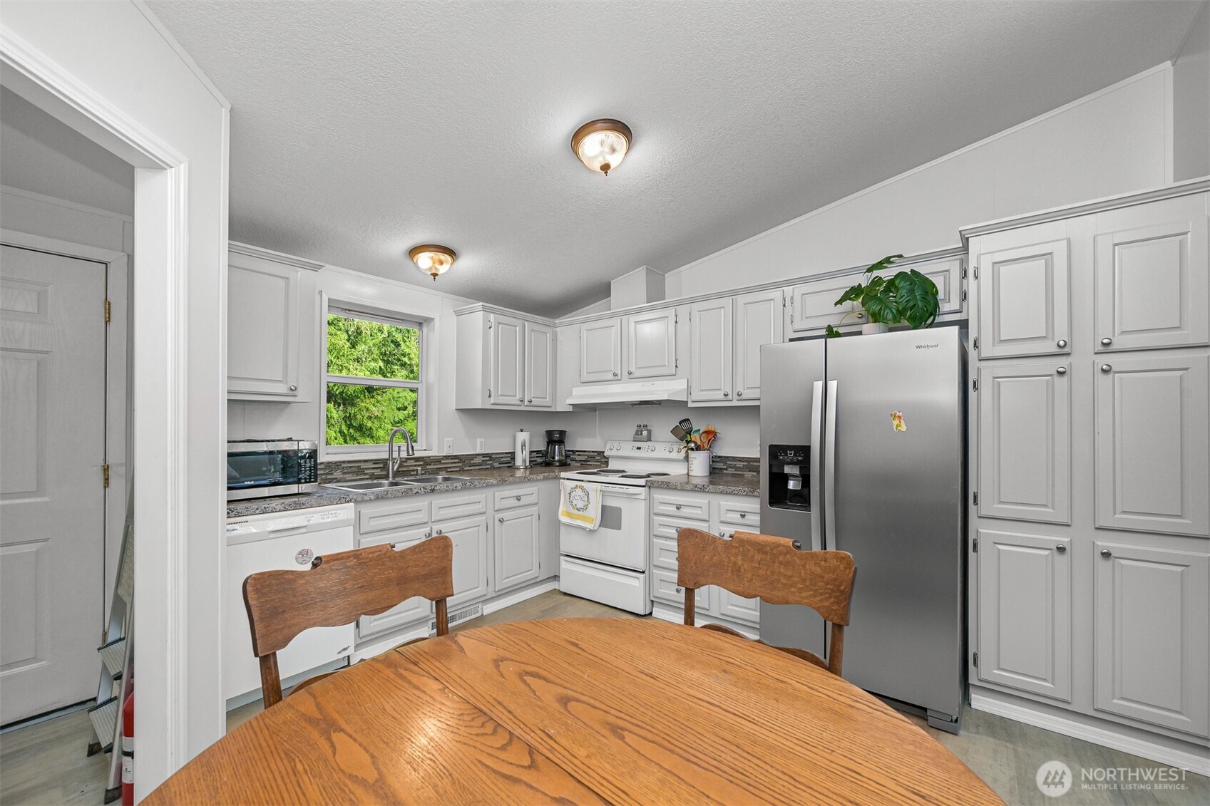 2174 Yew Street Road, Unit 22 Bellingham, WA 98229 - Photo 22 of 36 a kitchen with a refrigerator a stove top oven a sink dishwasher and white cabinets next to a window