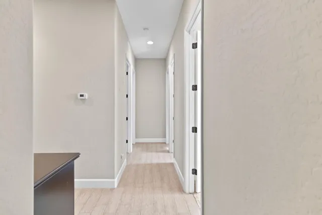 a view of a hallway with wooden floor and a bathroom
