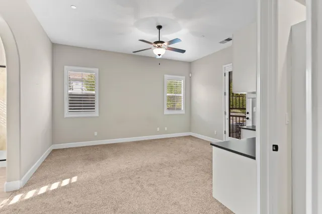 an empty room with chandelier fan and windows
