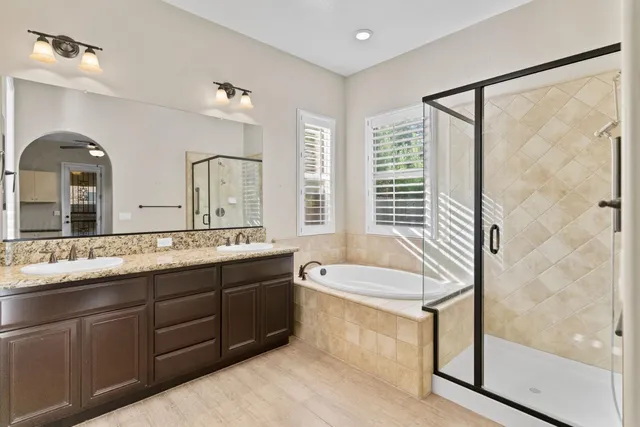 a spacious bathroom with a granite countertop tub sink shower and mirror