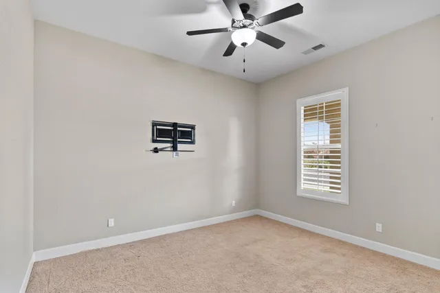 an empty room with windows and fan