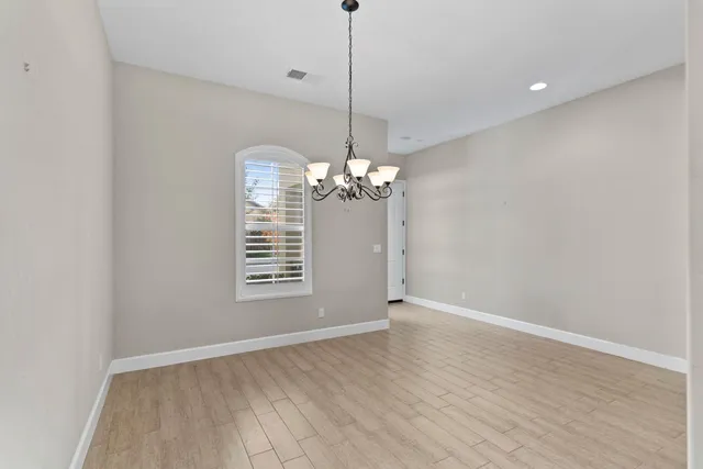 a view of a room with a chandelier fan and wooden floor