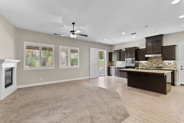 a large white kitchen with kitchen island granite countertop a stove top oven a sink a counter space and cabinets