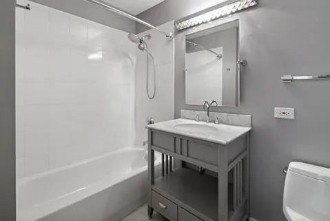a bathroom with a granite countertop sink a toilet and shower
