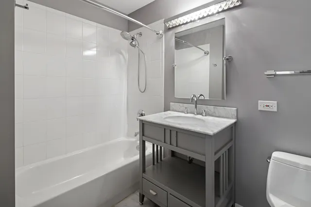 a bathroom with a granite countertop sink a toilet and shower