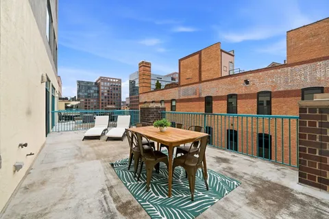a view of a roof deck with table and chairs a barbeque with wooden floor and fence