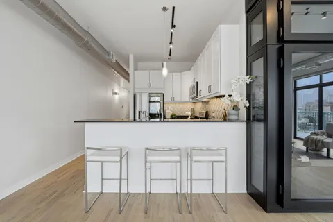a white kitchen with cabinets and chairs