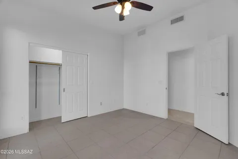 an empty room with chandelier fan and windows