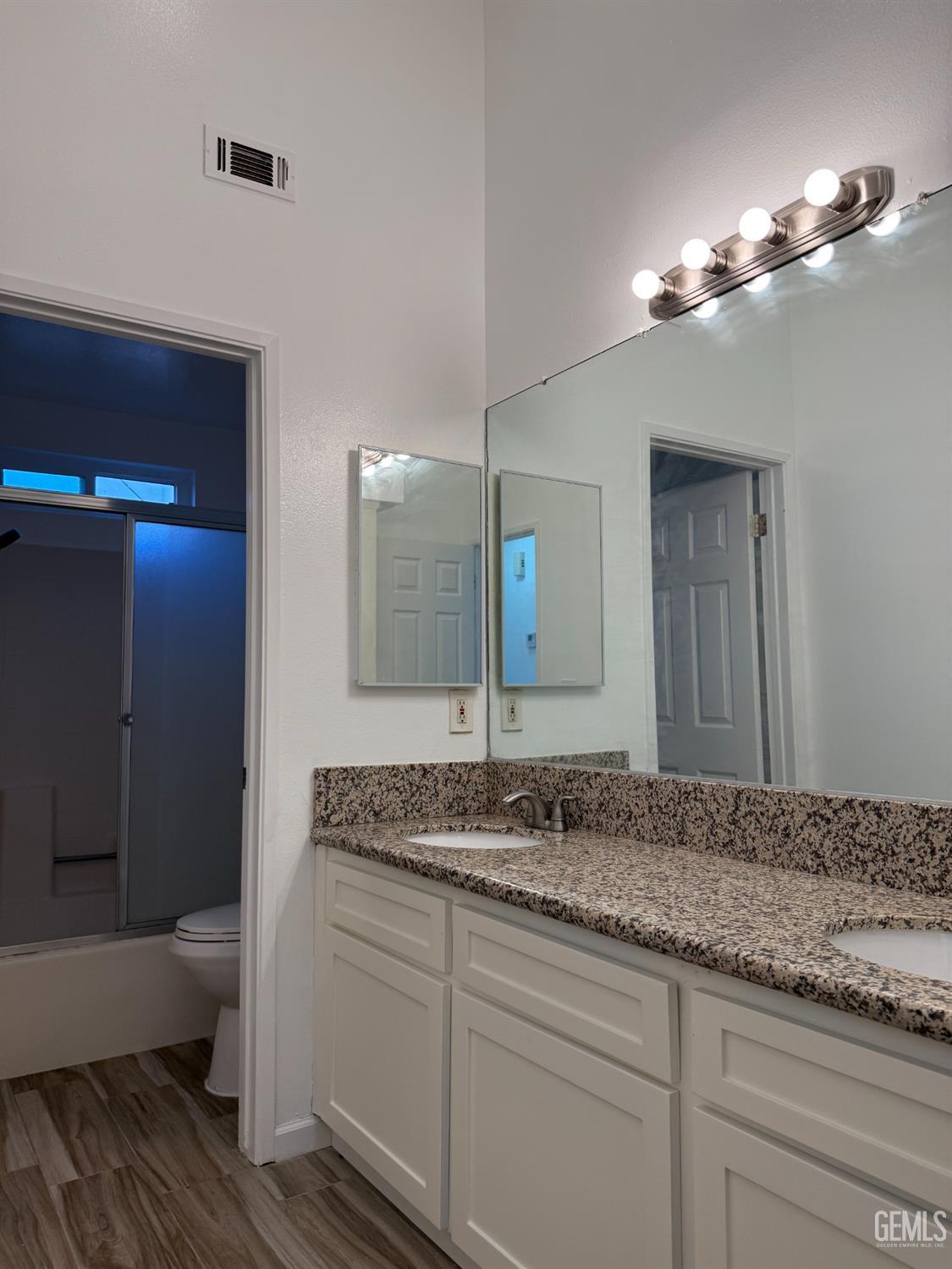 Undisclosed Address Bakersfield, CA 93307 - Photo 8 of 11 a bathroom with a granite countertop sink a large mirror and a toilet