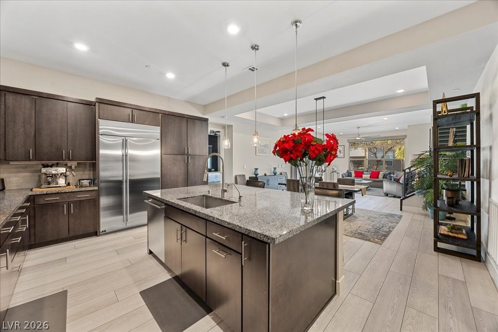 4262 Swift Street Las Vegas, NV 89135 - Photo 20 of 75 Kitchen with dark brown cabinetry, light stone counters, stainless steel built in refrigerator, pendant lighting, and recessed lighting