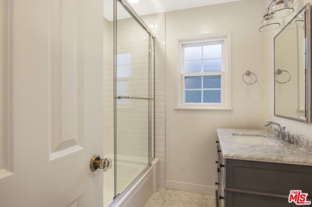 a bathroom with a granite countertop sink a mirror and shower