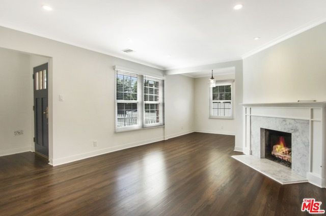 a view of an empty room with wooden floor fireplace and a window