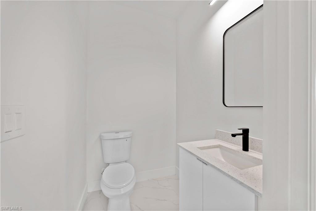 228 Connecticut Road Lehigh Acres, FL 33936 - Photo 17 of 21 a bathroom with a toilet a sink and mirror