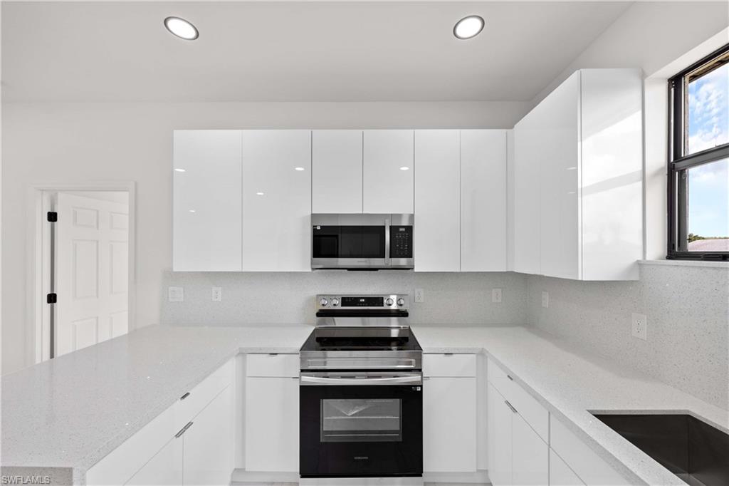 228 Connecticut Road Lehigh Acres, FL 33936 - Photo 9 of 21 a kitchen with white cabinets and a stove top oven