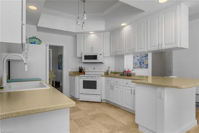 a kitchen with kitchen island white cabinets and white appliances