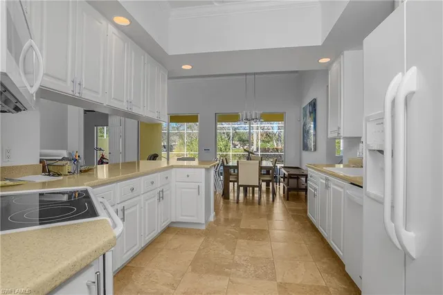 a large white kitchen with lots of counter top space a sink and stainless steel appliances