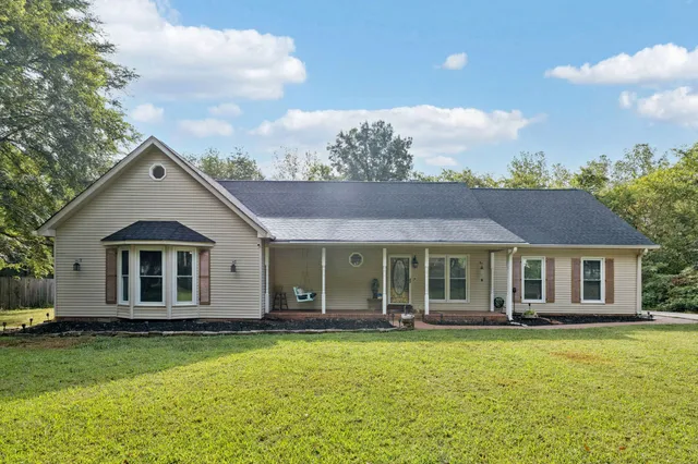 a view of a house with a big yard and large trees